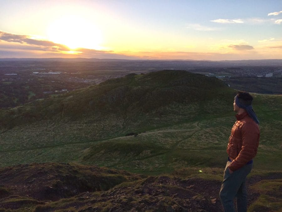 A man admiring the sunrise from Arthur's Seat, Edinburgh, Scotland
