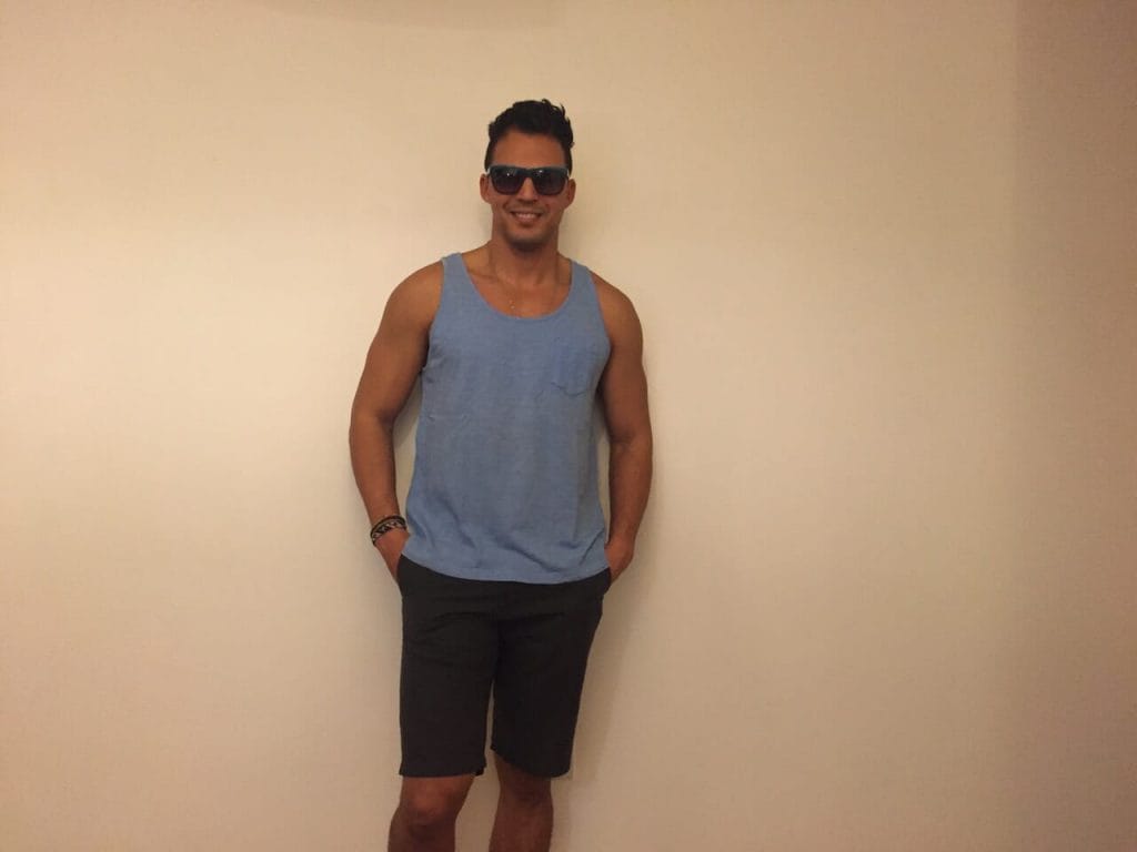 A man wearing a blue tank-top, black shorts and a blue sunglasses