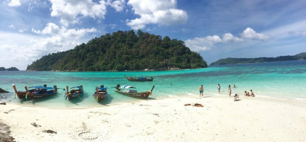 Koh Rokroy is a stunning island in the Tarutao National Marine Park, with crystalline turquoise water, soft white sand surrounded by mountains covered with exuberant vegetation. You can see also some long-tail boats and people enjoying this magnificent place