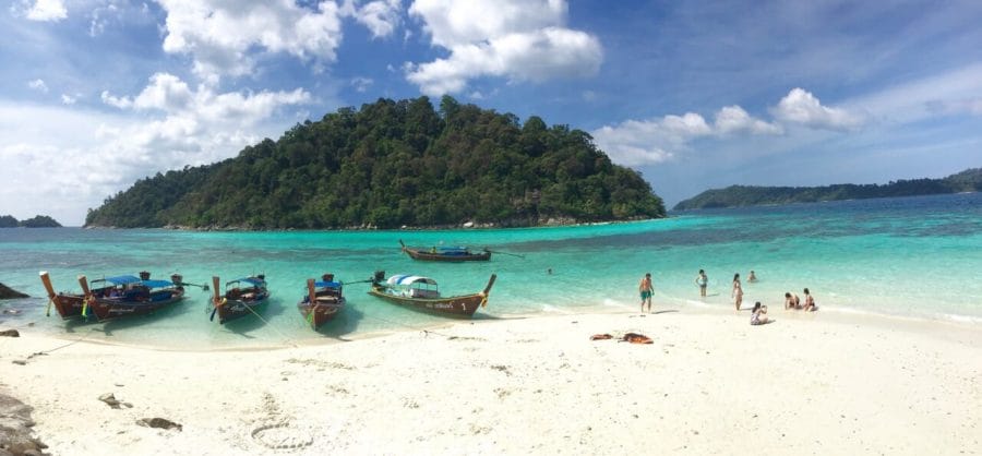 Koh Rokroy is a stunning island in the Tarutao National Marine Park, with crystalline turquoise water, soft white sand surrounded by mountains covered with exuberant vegetation. You can see also some long-tail boats and people enjoying this magnificent place