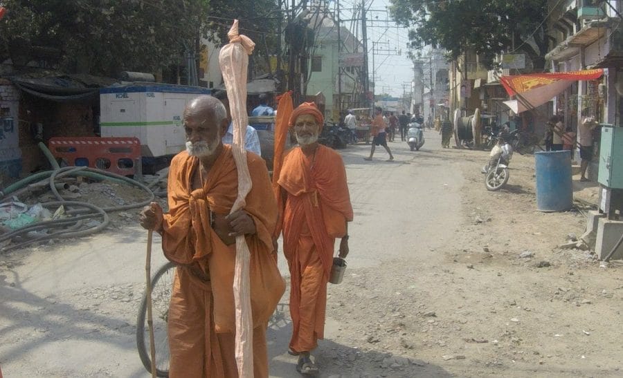 two men wearing an orange robe walking down on the street of Varanasi