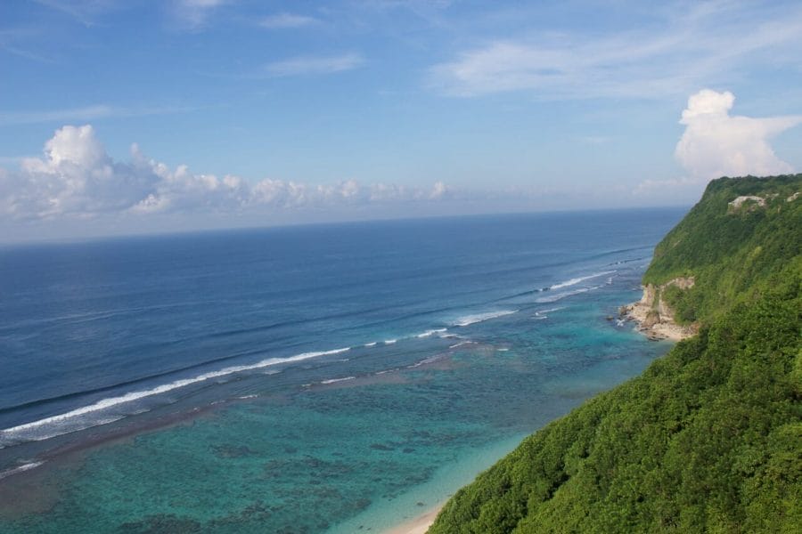 Karma Beach, Bali, is bordered by cliffs covered with vegetation and has crystalline blue water