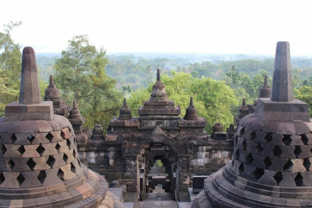 The stupas of Borobudur, which is located in an area with dense vegetation  on the island of Java, approximately 40Km (25mi) northwest of Yogyakarta and 86Km (53mi) west of Surakarta 