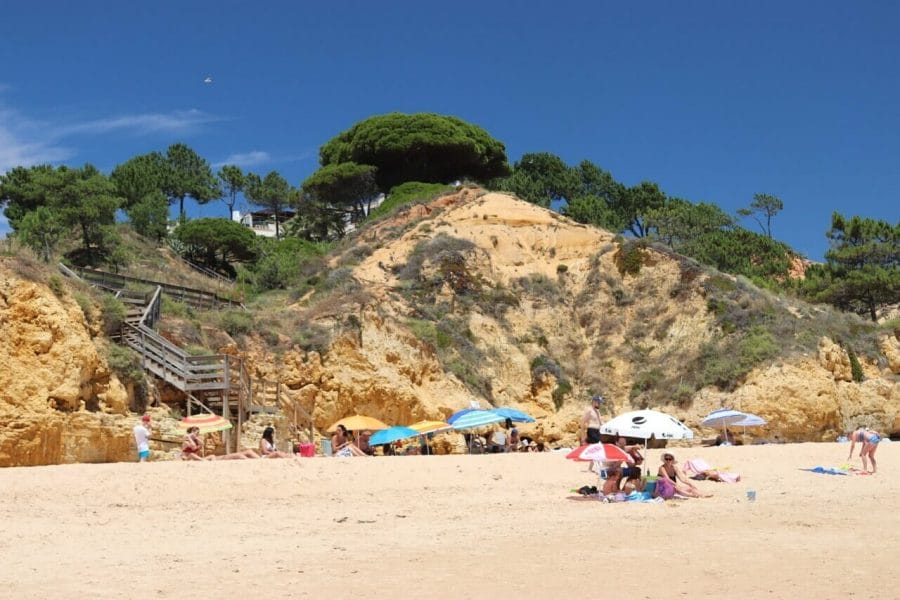 The section of Praia de Santa Eulália, Albufeira, Portugal, bordered by yellow cliffs topped with trees and low vegetation