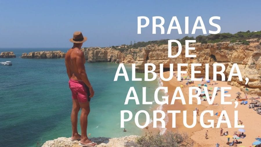 A man wearing a brown hat and a red short standing on the top of a cliff at Praia da Coelha, Albufeira, Portugal