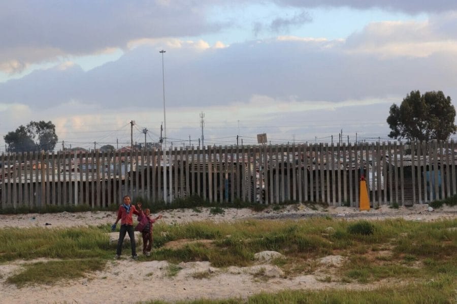 10 Things You Should Know Before Going to South Africa 5 Two kids playing in front near the roads and a township behind them, in the suburbs of Cape Town, South Africa