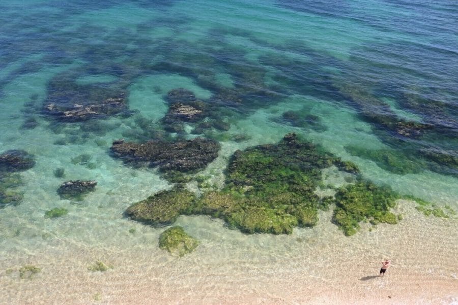 A água azul cristalina e as rochas cobertas por algas verdes da Praia da Coelha, Albufeira