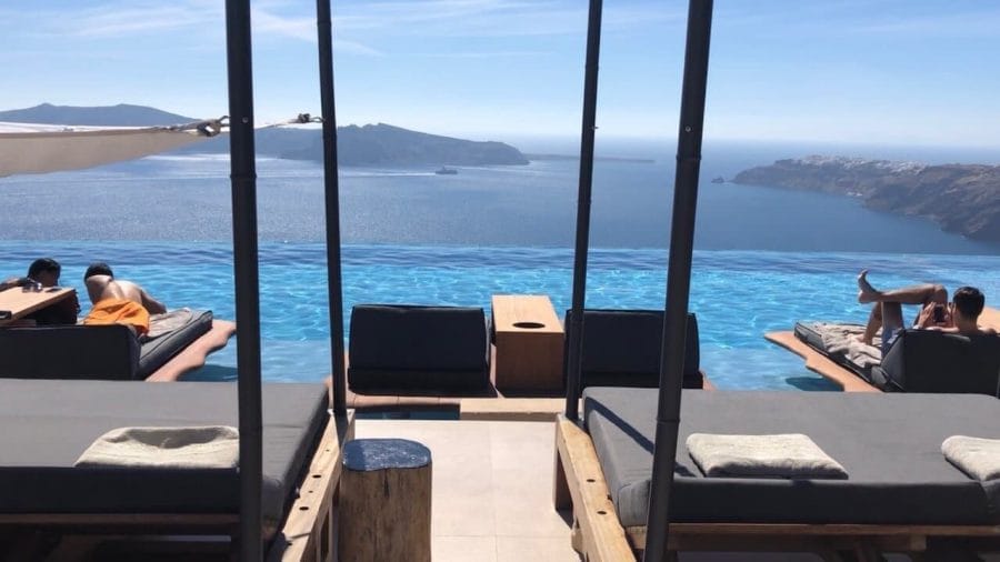 7 Best Things to Do in Imerovigli 17 people lying on lounge chairs by the infinity pool of the hotel Cavo Tagoo Santorini