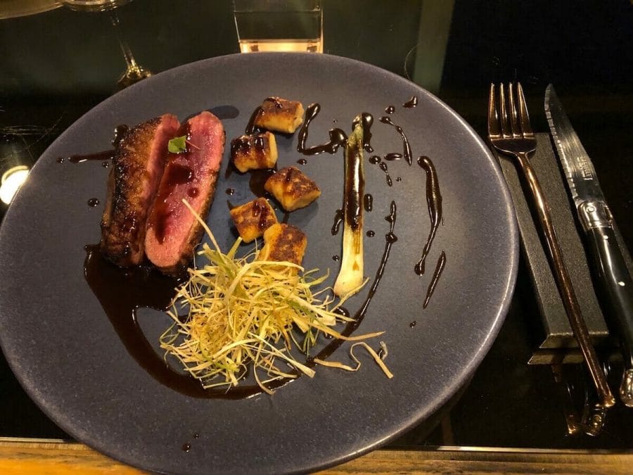 7 Best Things to Do in Imerovigli 20 Duck orange miso that comes with potato miso gnocchi, leeks, duck jus with orange served on a grey plate at La Maison Restaurant, Santorini