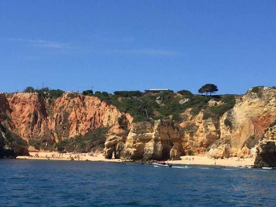View from the sea of Camilo Beach, Lagos, and its colossal limestone cliffs topped with low vegetation