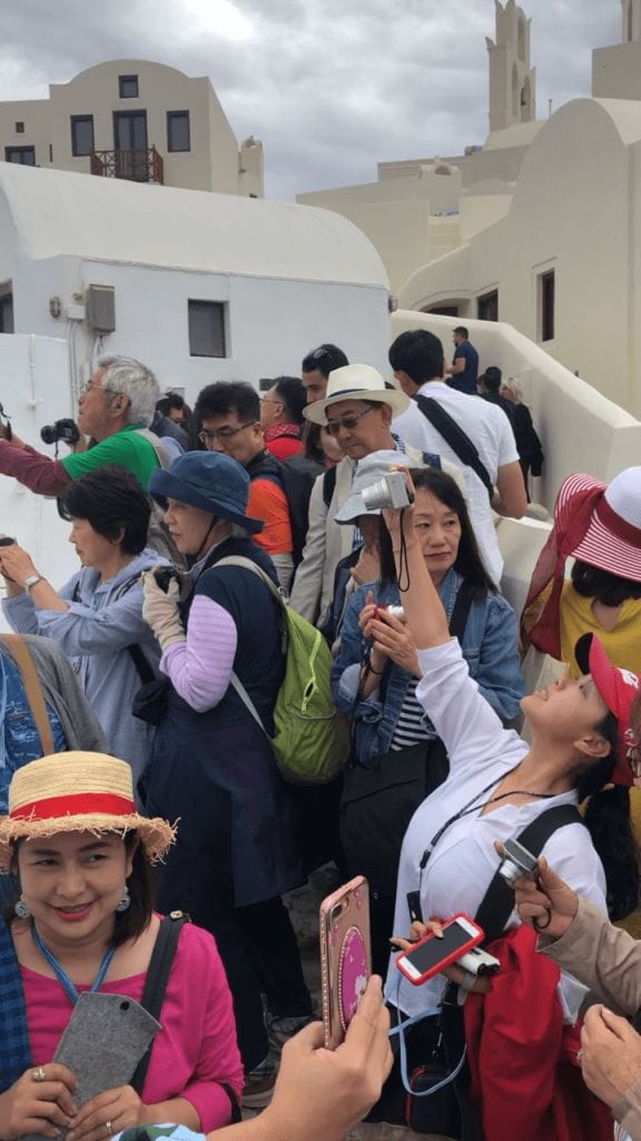 um grupo de turistas em uma rua estreita  em Oia, Sanorini