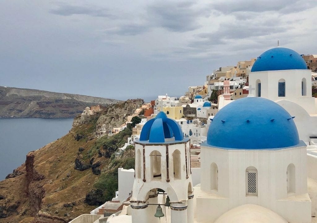 The famous three blue-domed church and house of the top of the cliff in the village of Oia, Santorini