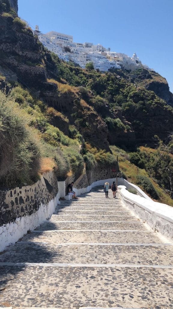 Two people walking down the 587 steps to Santorini old port