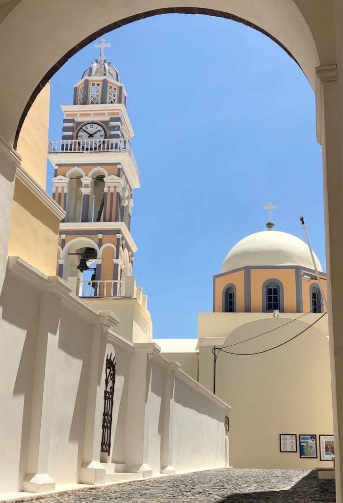 The beautiful bell tower and dome of Catholic Cathedral of Saint John the Baptist painted in pastel colours in Fira, Santorini