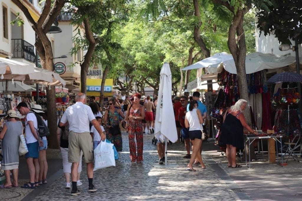 People shopping on a busy street in Old Town Albufeira with some stores on both sides and trees