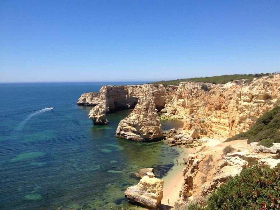 The orange-yellowish cliffs and blue water of Praia da Marinha in Lagoa, Algarve, Portugal.