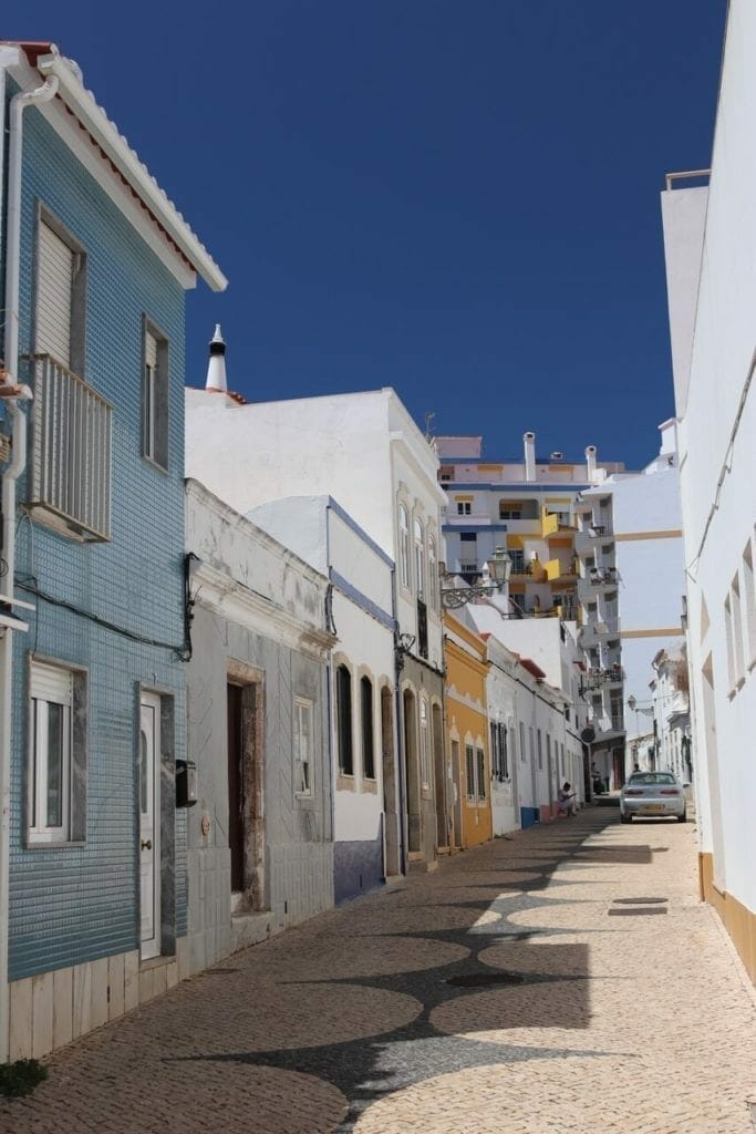 a coblestone street in Lagos Old Town, Portugal, with houses with pastel colours