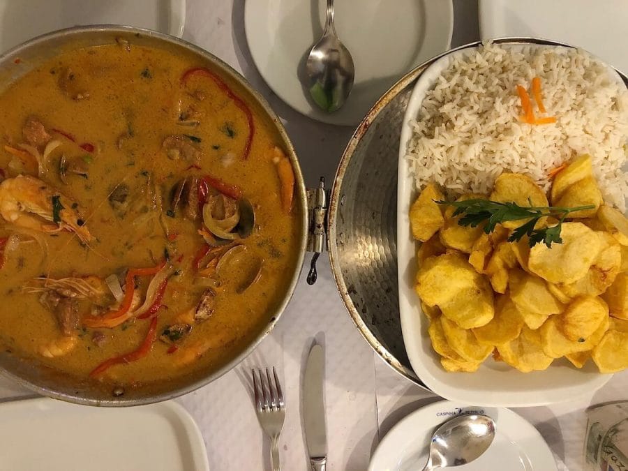 15 Best Things to Do in Faro Portugal - Tours & Activities Included 20 an aluminium bowl with typical Algarvian food, a white platter with some rice and potatoes, some cutleries and white plates on a white table at Cantinho do Petisco Restaurant in Lagos