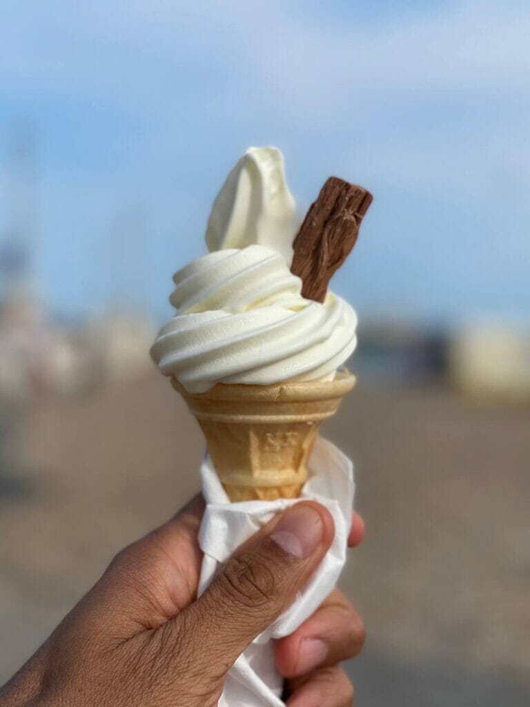 Uma mão segurando um sorvete de baunilha de floco 99 em Brighton Beach