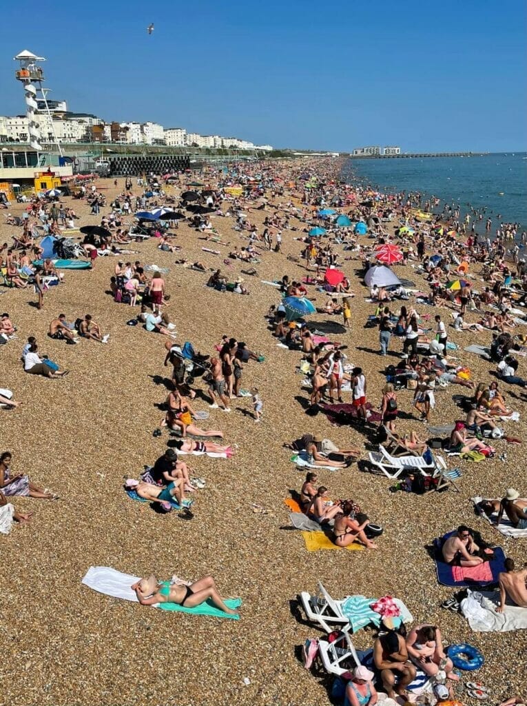 Pessoas tomando sol nas pedras de Brighton Beach, Brighton, Inglaterra
