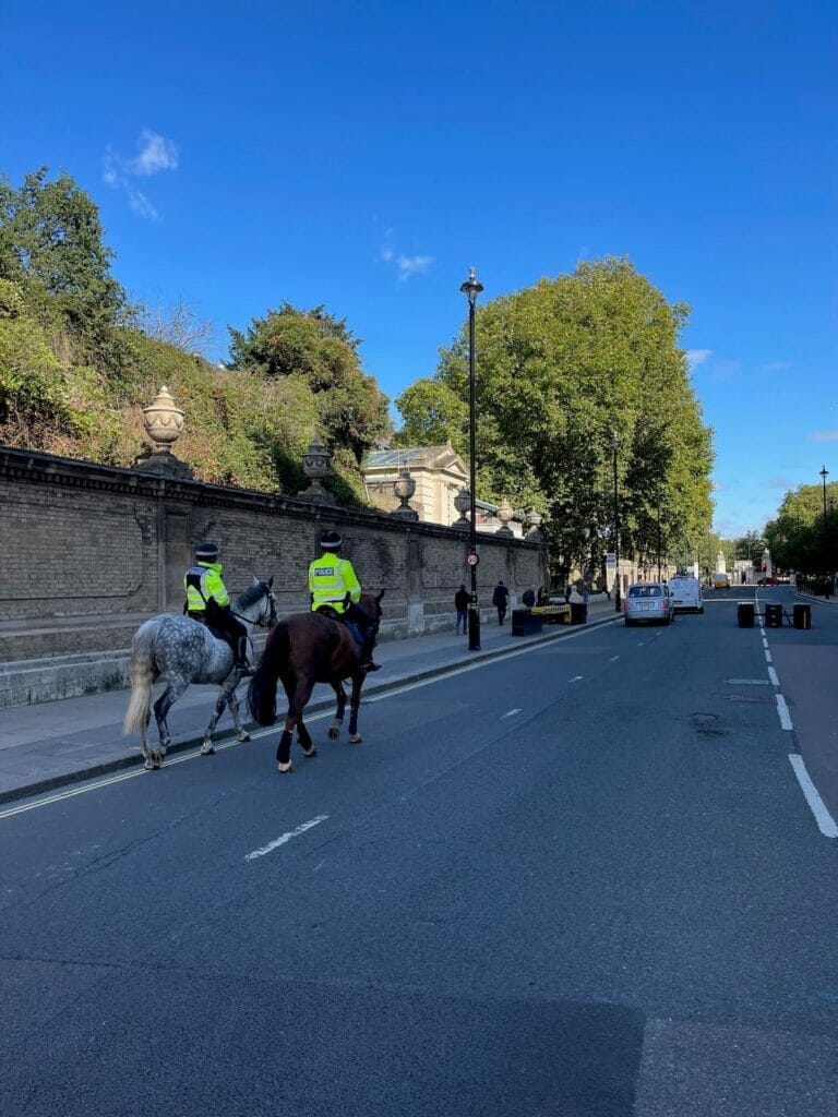 Dois policiais vestindo jaquetas verdes montando a cavalo na Buckingham Palace Road, Londres