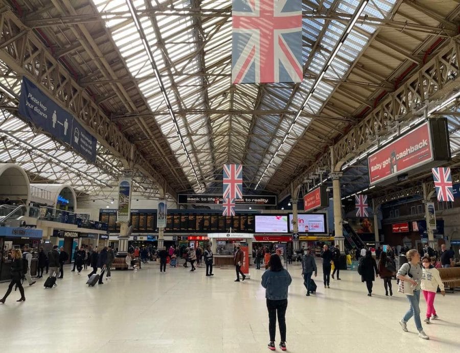 Estações de Metrô Mais Próximas do Palácio de Buckingham 6 Pessoas andando em Londres Victoria e algumas bandeiras da Inglaterra penduradas no teto
