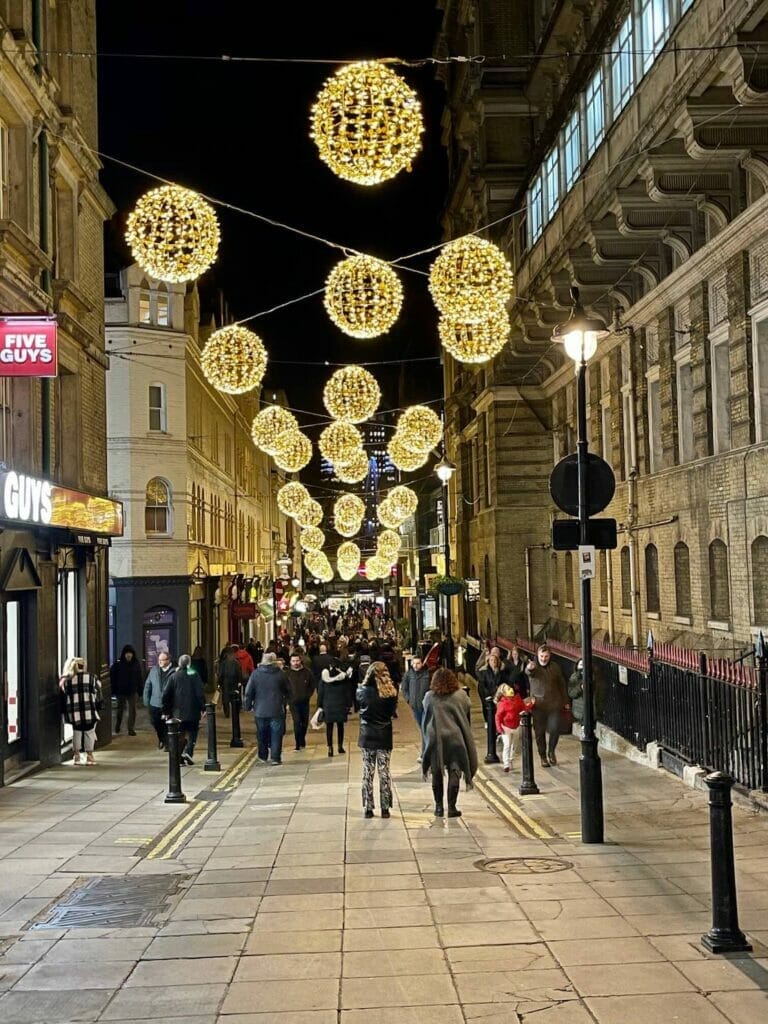 Pessoas andando na Villiers Street, Londres, que está decorada com globos de luz cintilantes para o Natal 2021