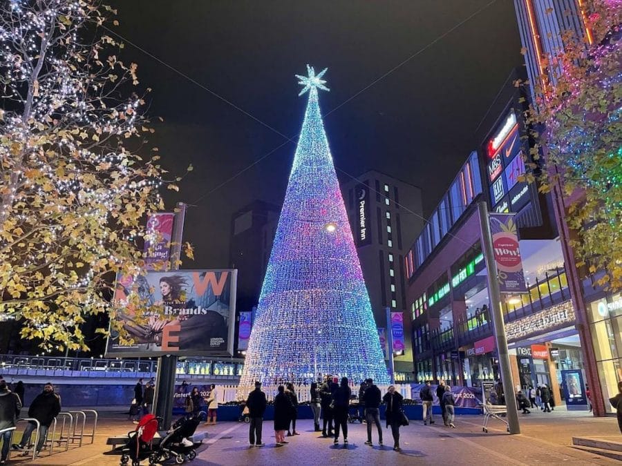 Pessoas de pé próximas a uma enorme árvore de Natal de LED em Wembley, Londres.