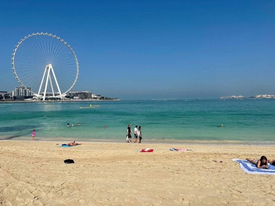 Pessoas caminhando e tomando sol na Praia JBR, Dubai