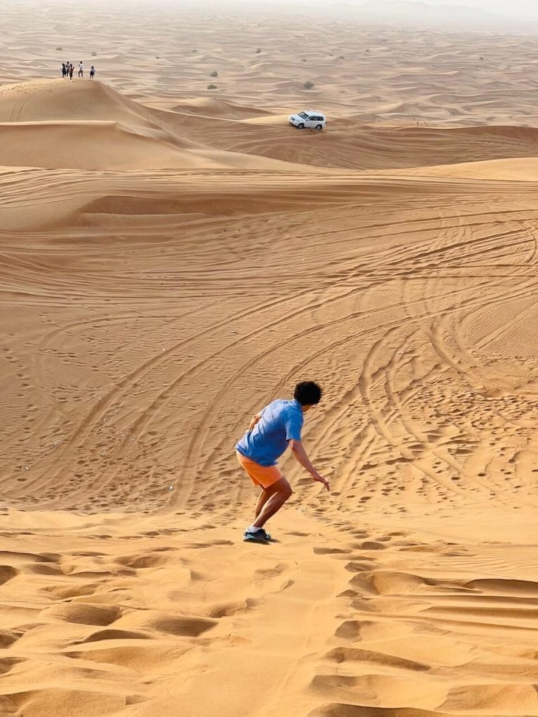 Cuánto Cuesta Viajar a Dubai en 2023 - Presupuesto & Consejos 3 Pericles Rosa haciendo sandboarding en el desierto de Al Lahbab. Dubai