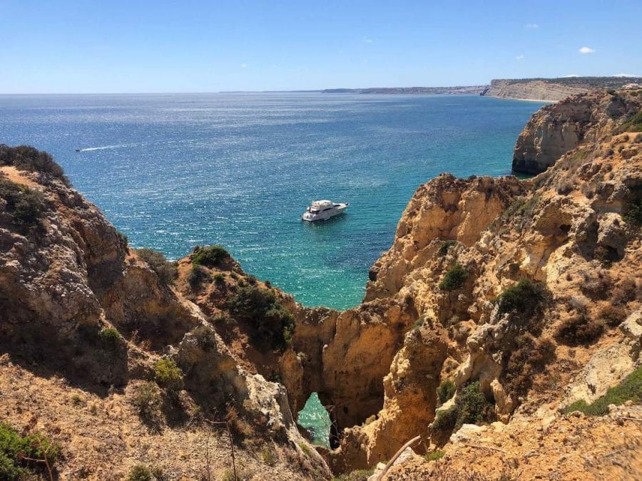 The view of a yacht sailing on the Algarvian coast in the city of Lagos from Ponta da Piedade trail