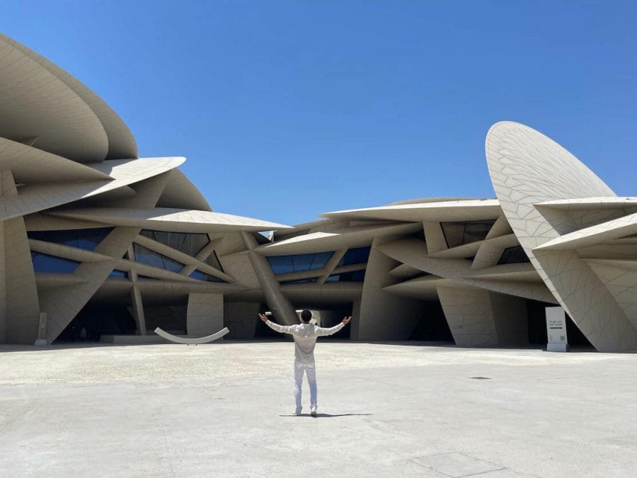 A man with the arms wide open in front of the National Museum of Qatar