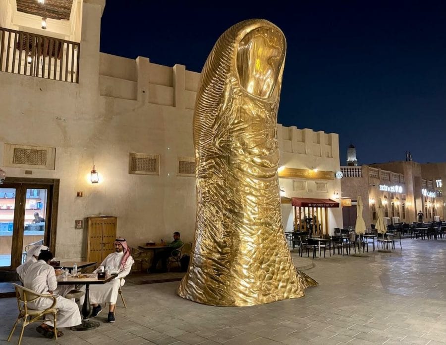 Some locals having coffee near the Gold Thumb Sculpture in Souq Waqif, Doha,Qatar
