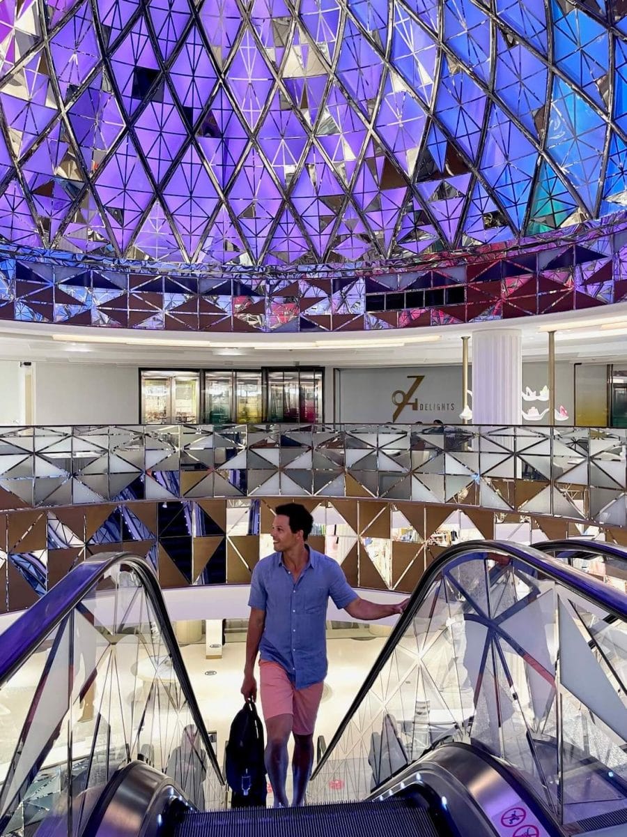 A man at Galeries Lafayette, Doha, going up on the escalators with a glass dome in the background