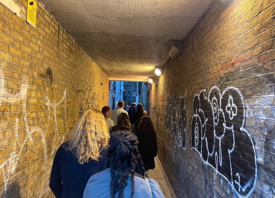 A Jack the Ripper group tour walking on an alley in Spitalfields, East London
