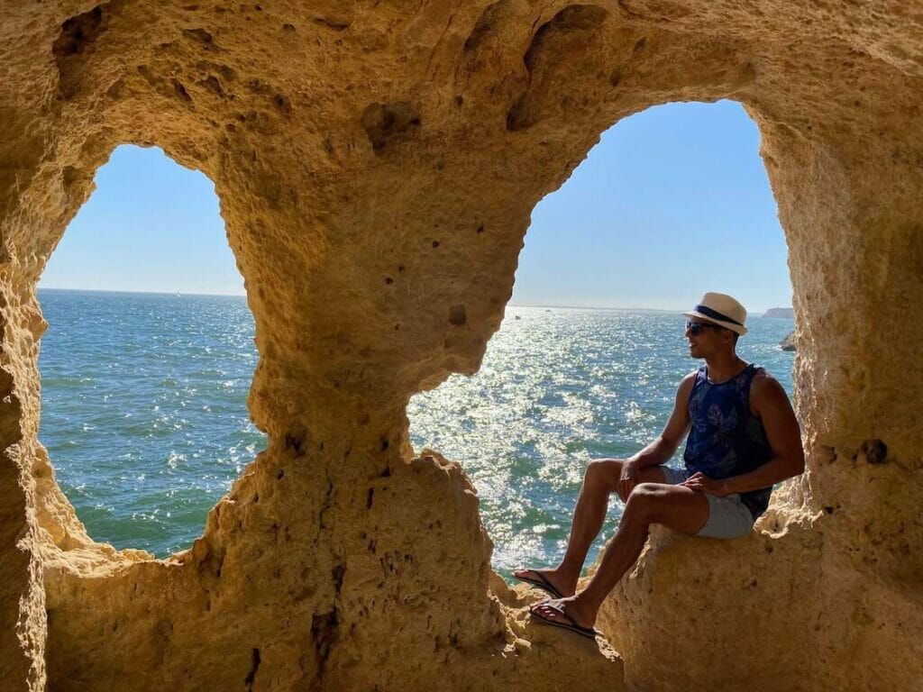 A man inside "A Boneca", a cave featuring two eroded arches providing great views out over the sea, in Algar Seco, Carvoeiro, Portugal