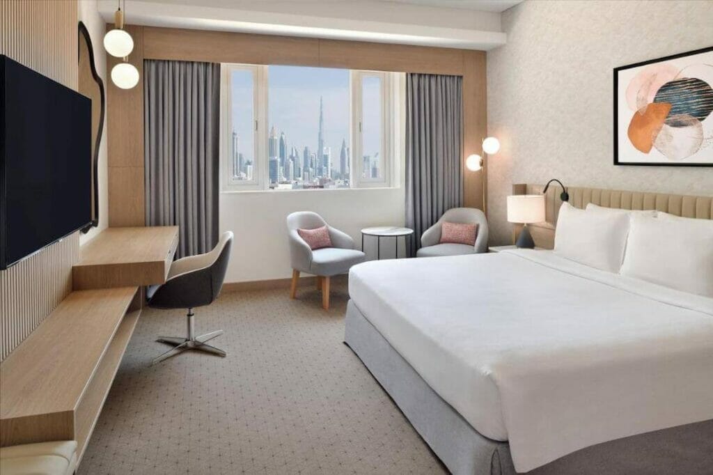 A double-bed room with a desk, seating area and the Bujr Kalifa view at Crowne Plaza - Dubai Jumeirah on Jumeirah Beach