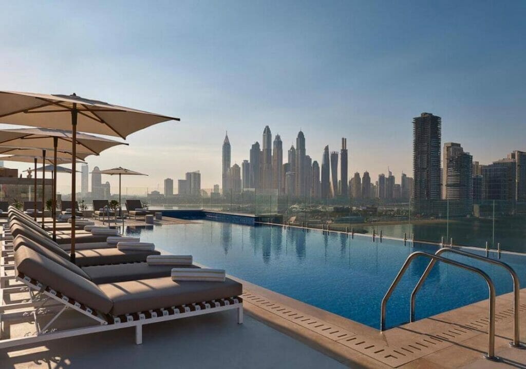 An infinity swimming pool on the rooftop with some buildings in the backdrop at Voco Dubai The Palm Hotel, Palm Jumeirah Island, Dubai