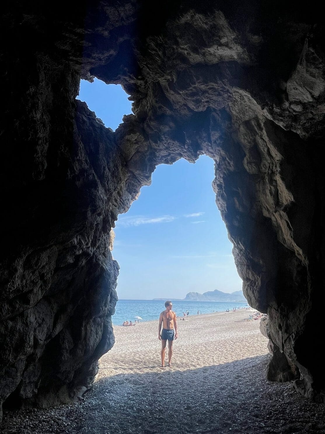 Um homem posando para uma foto na caverna de Traganou Beach, Rhodes, Grécia