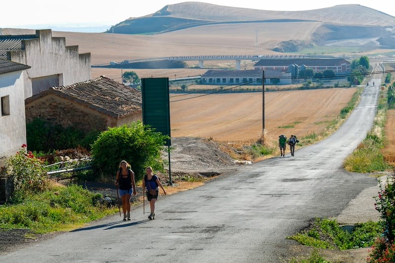 Pilgrims walking along a famous Camino de Santiago walking road in the picturesque countryside of Northern Spain, Europe. 