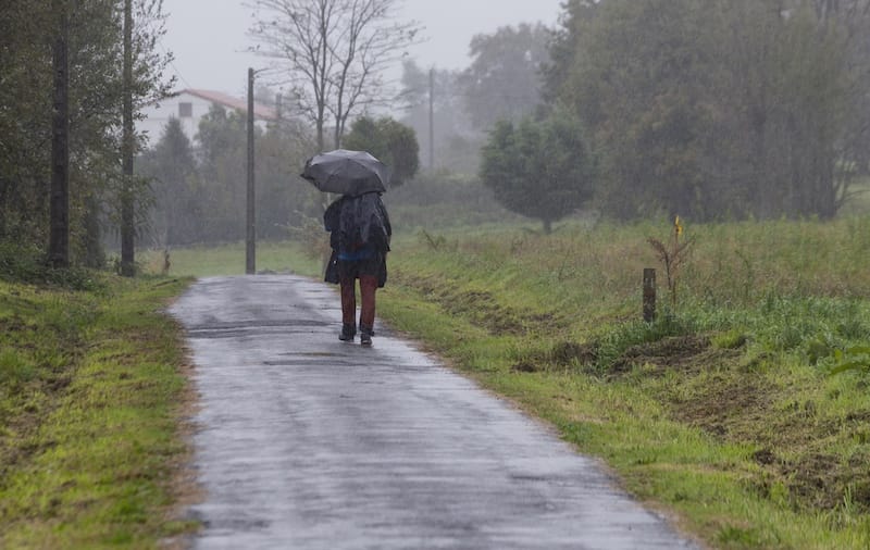 A pilgrim with an umbrella in the rain on the Portuguese Camino de Santiago in A Escravitude